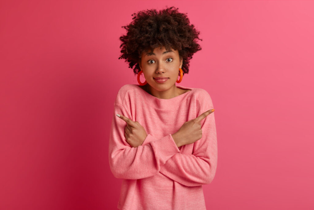 mujer indecisa sobre fondo rosado. mujer tomando una decisión. mujer en una encrucijada. elegir.