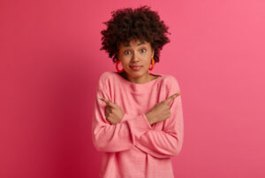 Blog 5 mujer indecisa sobre fondo rosado. mujer tomando una decisión. mujer en una encrucijada. elegir.