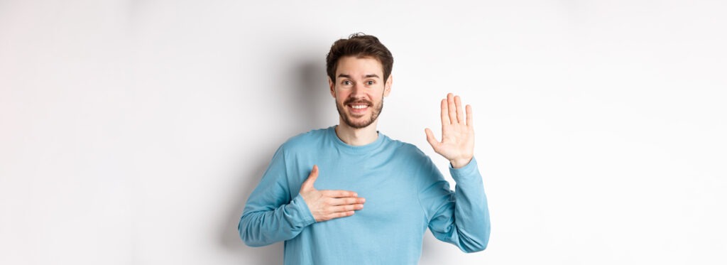 smiling hosent man raising arm hold hand heart making promise tell truth swear give oath s